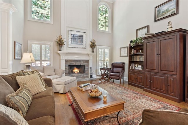 living room with a towering ceiling, a fireplace, and light hardwood / wood-style floors