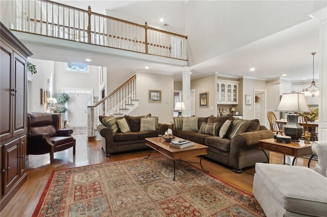 living room with crown molding, hardwood / wood-style flooring, decorative columns, and a towering ceiling