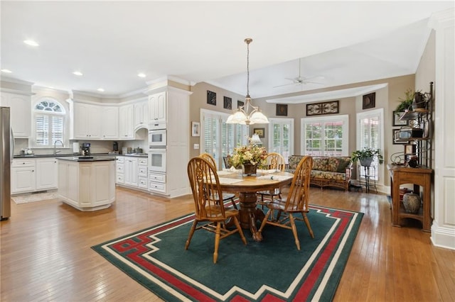 dining room featuring lofted ceiling, sink, ceiling fan with notable chandelier, and light hardwood / wood-style flooring