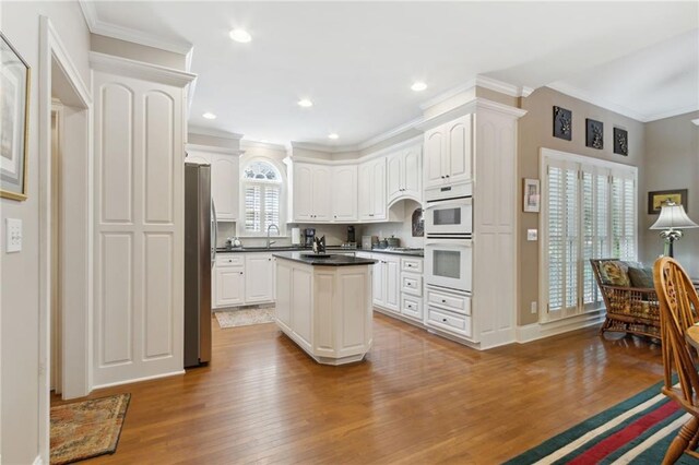 kitchen featuring sink, white cabinetry, light hardwood / wood-style flooring, ornamental molding, and stainless steel fridge