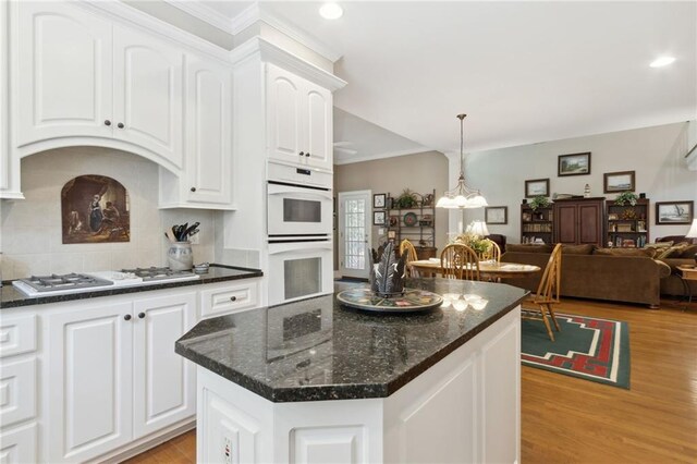 kitchen featuring white cabinetry, white double oven, a center island, and gas stovetop