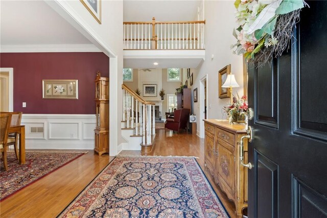 foyer featuring a towering ceiling, ornamental molding, and light wood-type flooring