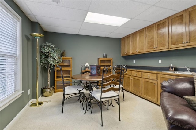 carpeted dining room featuring a paneled ceiling and sink