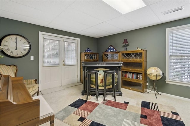 sitting room with a paneled ceiling and light colored carpet