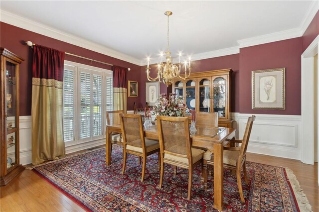 dining space with an inviting chandelier, wood-type flooring, and crown molding