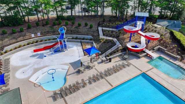 view of swimming pool with a community hot tub, a water slide, and a patio