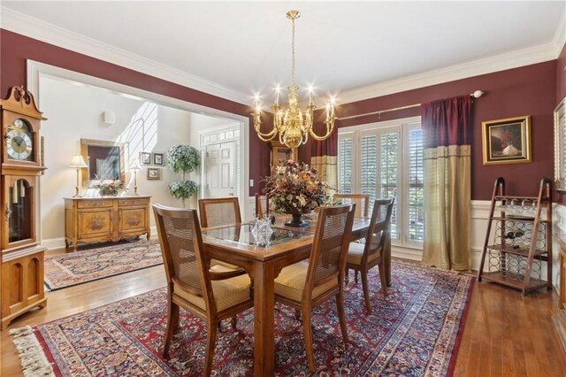 dining area featuring hardwood / wood-style floors, crown molding, and a chandelier