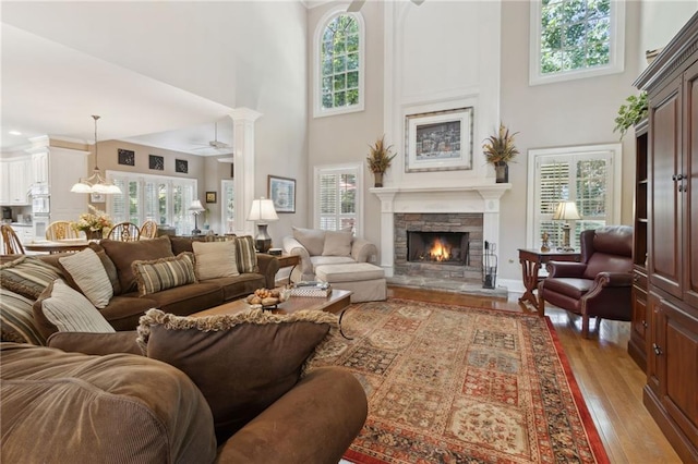 living room featuring a high ceiling, plenty of natural light, a fireplace, and light hardwood / wood-style floors