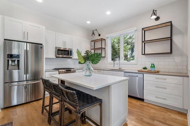 kitchen with a center island, sink, appliances with stainless steel finishes, a kitchen breakfast bar, and white cabinets