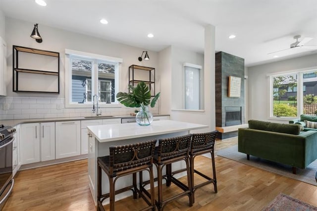 kitchen featuring a kitchen bar, white cabinets, a kitchen island, light hardwood / wood-style flooring, and sink