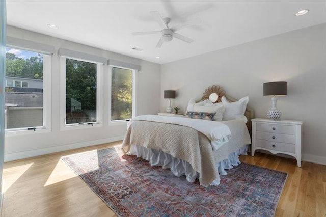 bedroom with ceiling fan, light hardwood / wood-style floors, and multiple windows