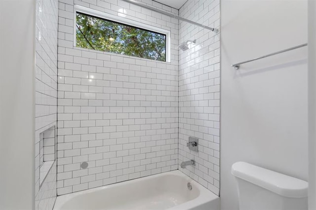 bathroom with tiled shower / bath combo and toilet