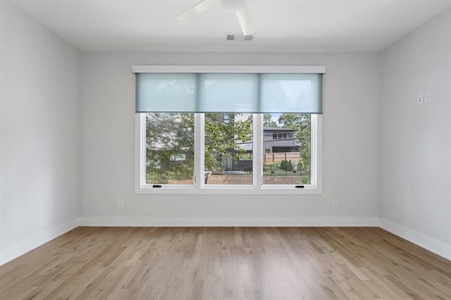 empty room featuring ceiling fan, light hardwood / wood-style flooring, and plenty of natural light