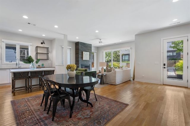 dining room with a fireplace, sink, and light hardwood / wood-style flooring