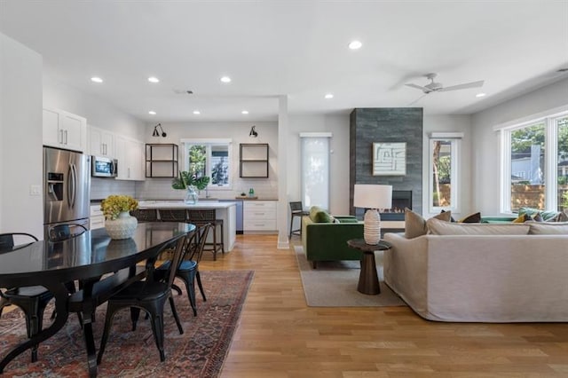 dining area featuring ceiling fan, light hardwood / wood-style flooring, and a tiled fireplace