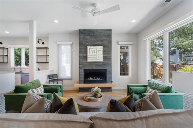 living room featuring ceiling fan, a fireplace, and light hardwood / wood-style flooring