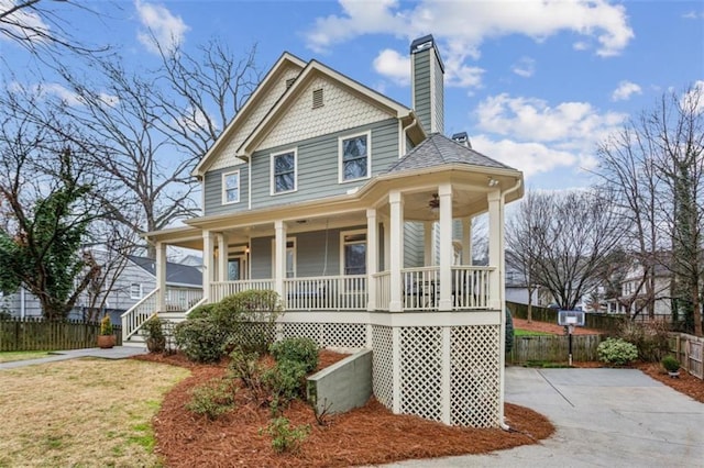 view of front of property featuring a chimney, covered porch, fence, driveway, and a front lawn