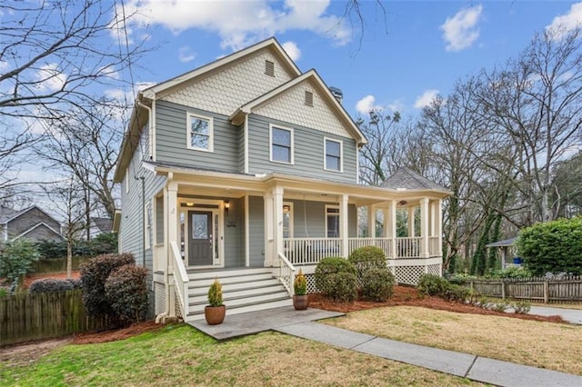 view of front facade with covered porch, fence, and a front lawn