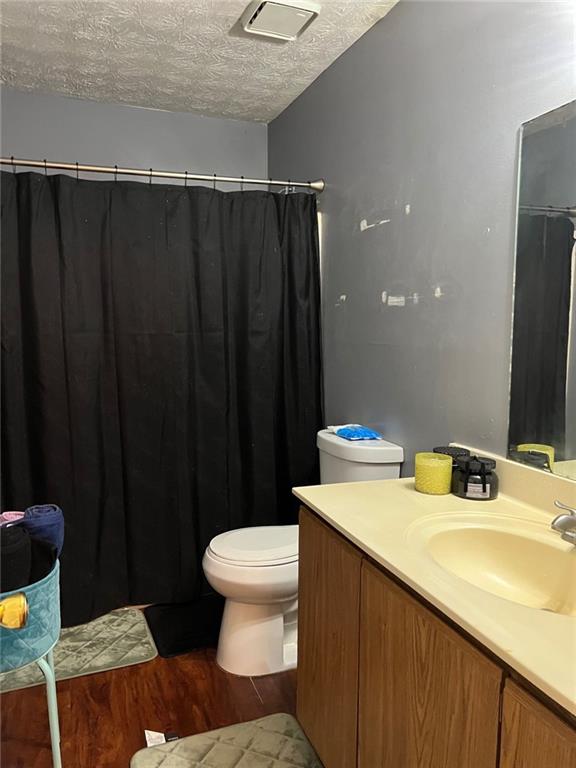 bathroom with toilet, vanity, a textured ceiling, and hardwood / wood-style flooring