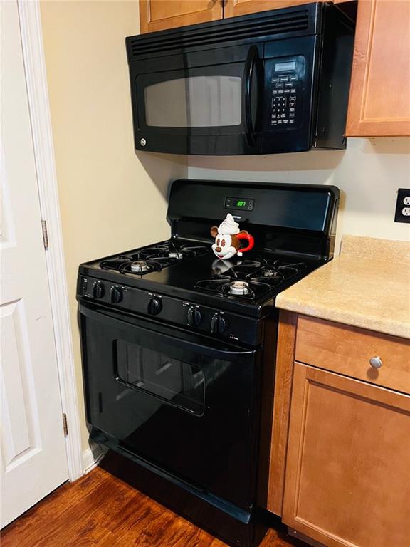 kitchen featuring dark hardwood / wood-style flooring and black appliances