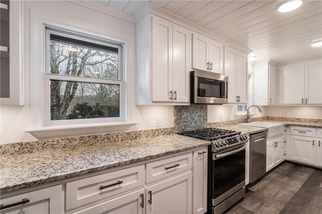 kitchen featuring white cabinetry, sink, gas range, and light stone countertops