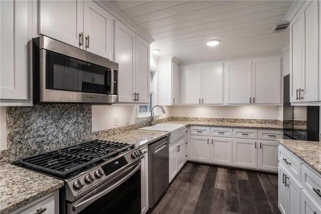 room details with white cabinetry, sink, and light stone counters