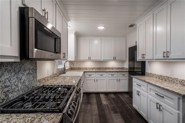 kitchen featuring white cabinetry, light stone counters, and fridge