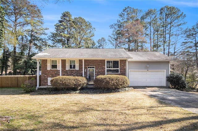 raised ranch featuring driveway, fence, a front yard, an attached garage, and brick siding