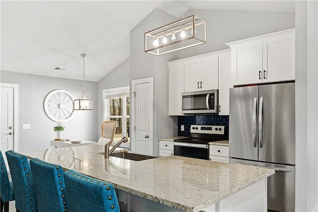 kitchen with visible vents, vaulted ceiling, appliances with stainless steel finishes, white cabinetry, and a sink