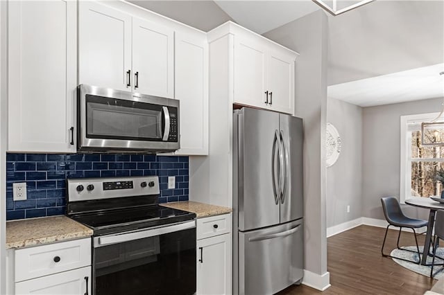 kitchen featuring baseboards, dark wood-style flooring, appliances with stainless steel finishes, white cabinetry, and backsplash