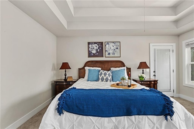 carpeted bedroom with baseboards and a raised ceiling