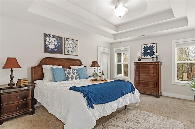 bedroom featuring a raised ceiling, carpet flooring, baseboards, and visible vents