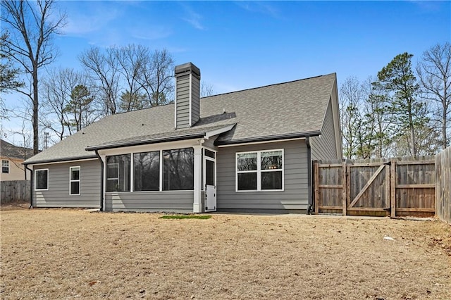 rear view of house with a shingled roof, fence, a chimney, a sunroom, and a gate