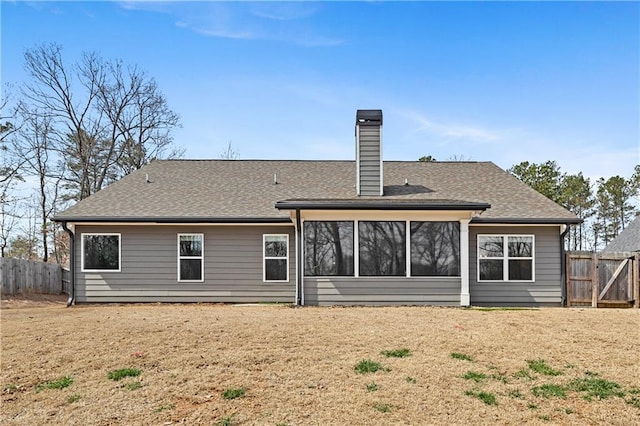 rear view of property featuring a shingled roof, fence, and a chimney