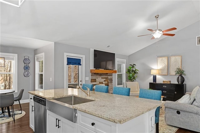 kitchen featuring open floor plan, dark wood-style flooring, stainless steel dishwasher, white cabinetry, and a sink