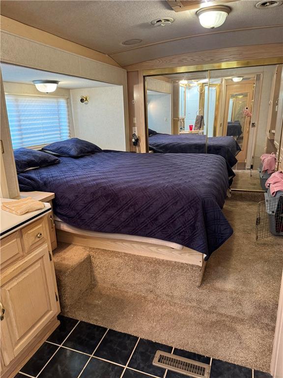 bedroom featuring lofted ceiling, dark tile patterned flooring, and a textured ceiling