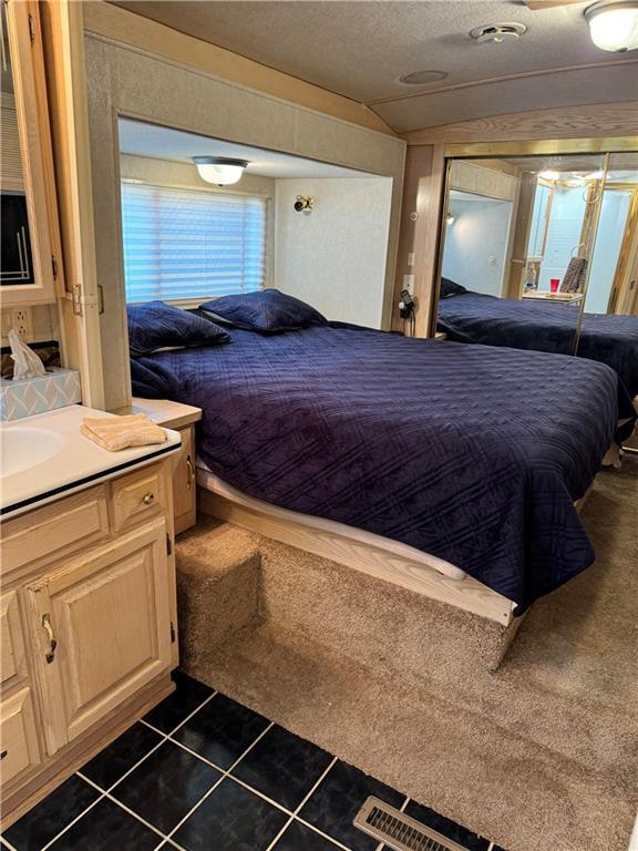 bedroom featuring dark tile patterned floors, vaulted ceiling, and a textured ceiling