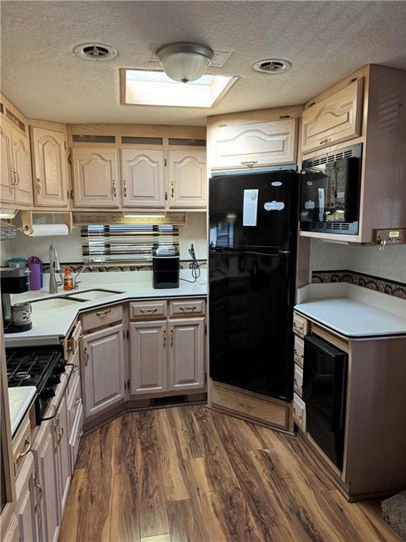 kitchen with stainless steel gas cooktop, sink, black fridge, a textured ceiling, and dark hardwood / wood-style flooring