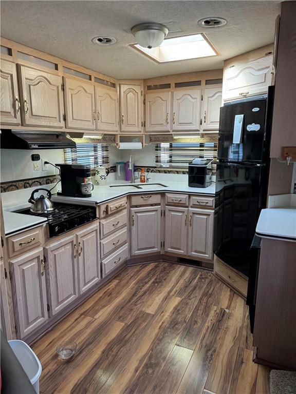 kitchen featuring dark hardwood / wood-style flooring, sink, a textured ceiling, and black appliances