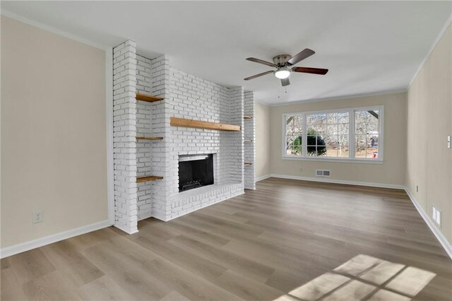 unfurnished living room featuring a fireplace, hardwood / wood-style floors, ceiling fan, and crown molding