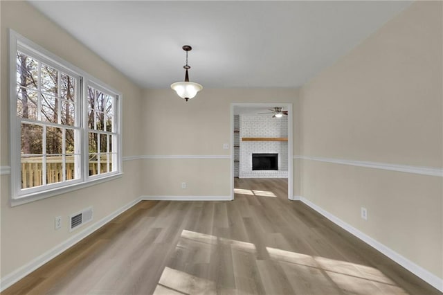 unfurnished living room with wood-type flooring, a brick fireplace, and ceiling fan