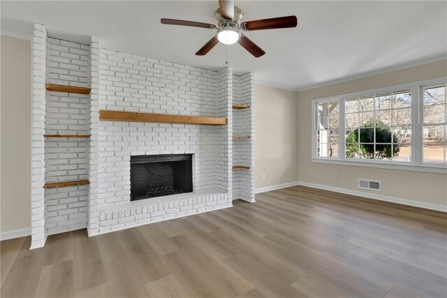 unfurnished living room featuring a fireplace, hardwood / wood-style flooring, ceiling fan, and crown molding