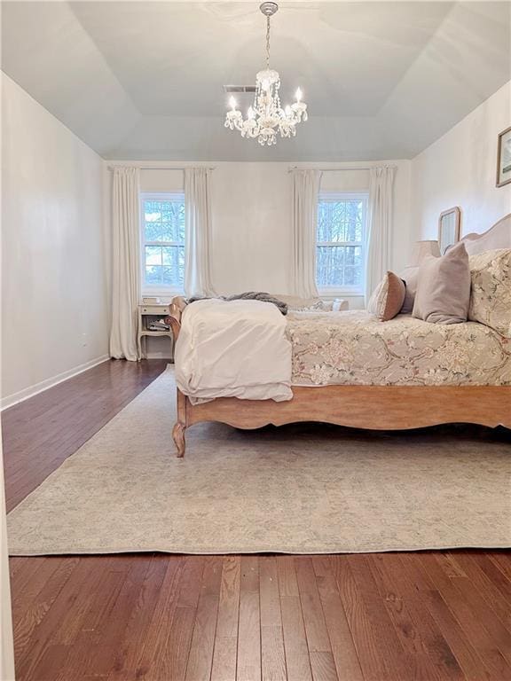 bedroom with multiple windows, hardwood / wood-style floors, and a tray ceiling