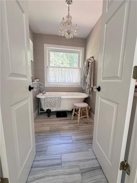 bathroom featuring an inviting chandelier, wood-type flooring, and a bathing tub