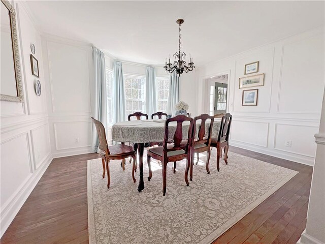 dining space with ornamental molding, dark wood-type flooring, and an inviting chandelier