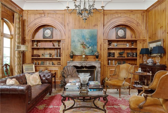 living area with built in features, an inviting chandelier, a fireplace, and wood walls