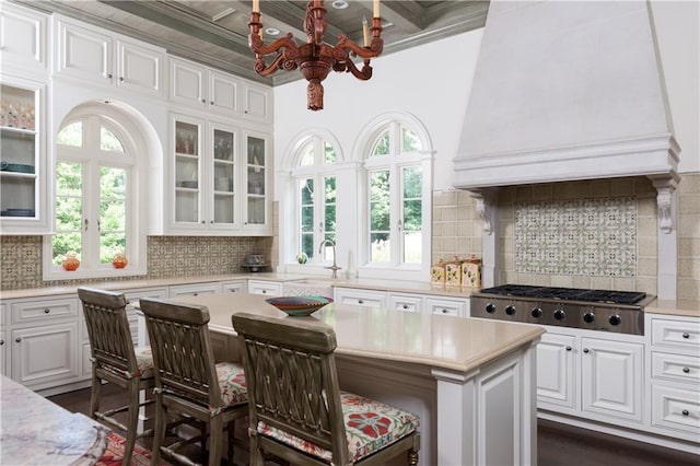 kitchen featuring a healthy amount of sunlight, white cabinets, a kitchen island, a breakfast bar area, and stainless steel gas cooktop