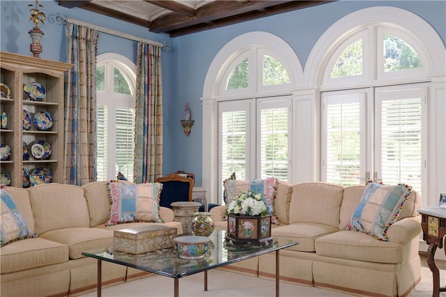 living room with beam ceiling, a wealth of natural light, and a high ceiling