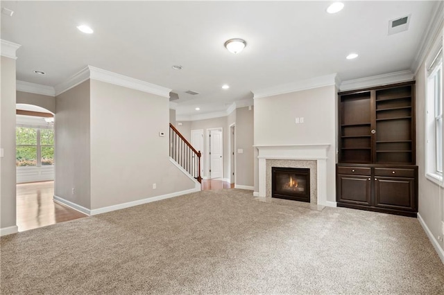 unfurnished living room featuring crown molding, light colored carpet, and a fireplace