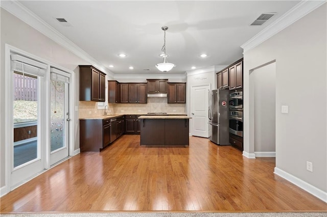 kitchen featuring sink, decorative light fixtures, a center island, dark brown cabinets, and stainless steel appliances